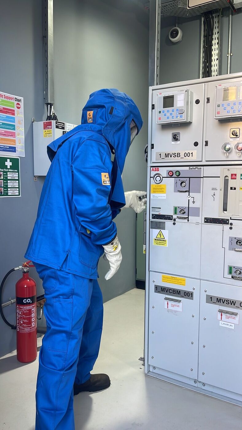 CurrenTSea engineer in arc-flash PPE operating medium-voltage switchgear